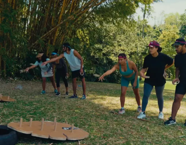 Des participants lancent des palets vers le plateau en bois du Disbwa, sous les bambous